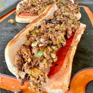 cheesesteak loaded hotdogs on a Cutting board