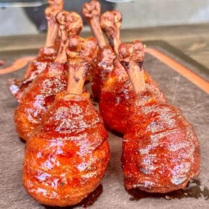 Smoked chicken lollipops wrapped in bacon and glazed with BBQ sauce