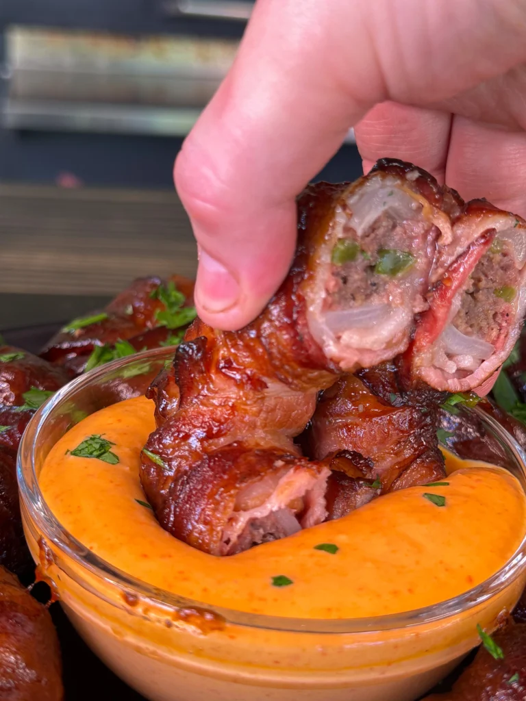 dipping the bacon wrapped burger in the sauce
