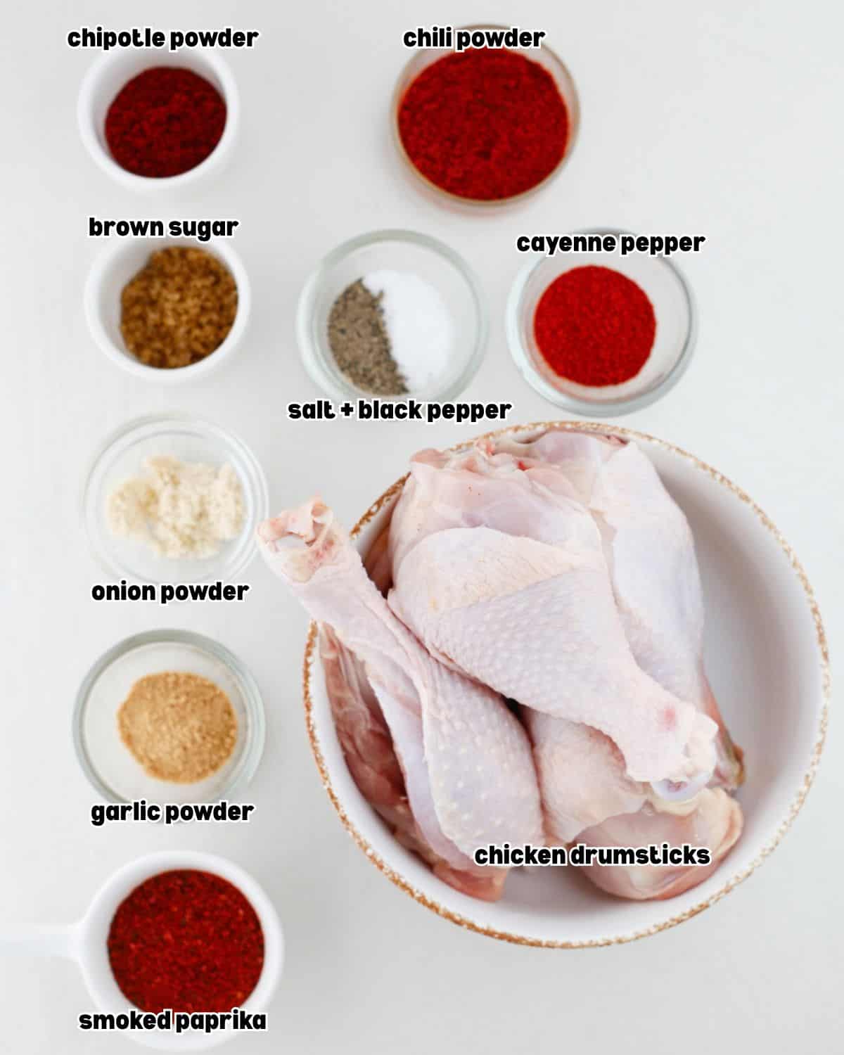 raw chicken drumsticks and other ingredients for grilled butterflied chicken drumsticks recipe placed in separate bowls, on a kitchen countertop.