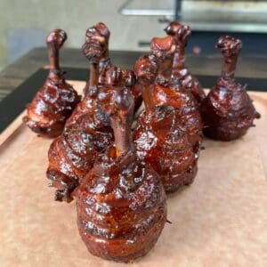 Honey jalapeño chicken lollipops wrapped in bacon and glazed with honey jalapeño BBQ sauce