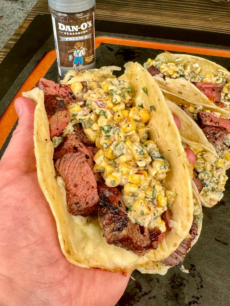 holding an elote steak tacos