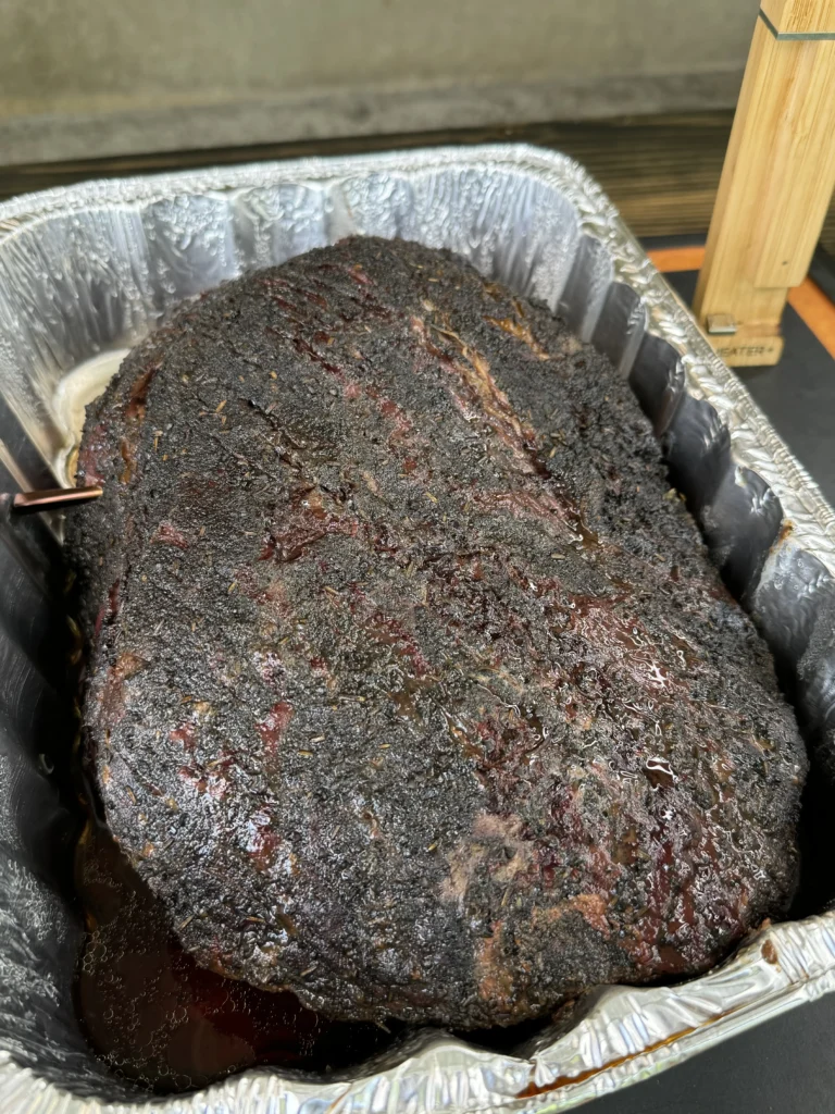 brisket in a pan on the smoker