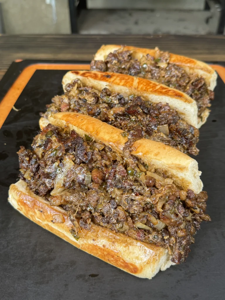 3 cheesesteaks in a row on the cutting board