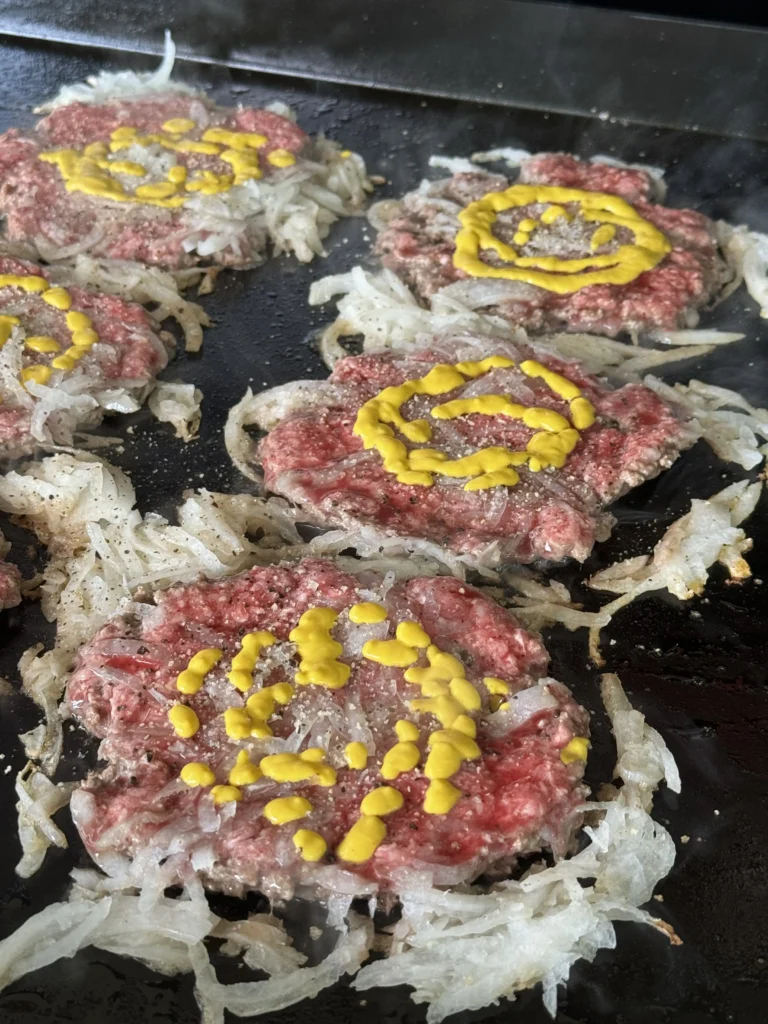 smash burgers with onions on the flat top