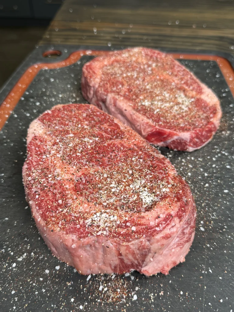 seasoned ribeyes on the cutting board