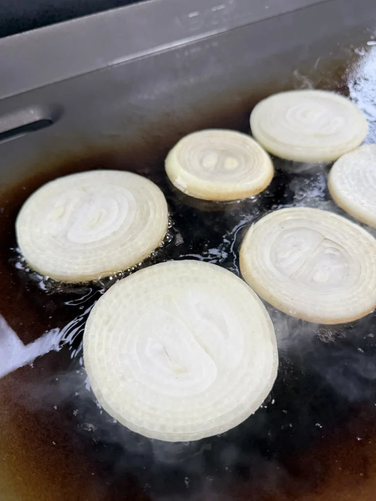 cooking onions on the griddle for the patty melt