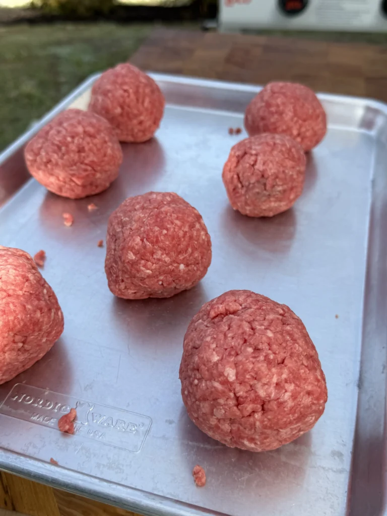 Raw ground beef balls on pan before smashing