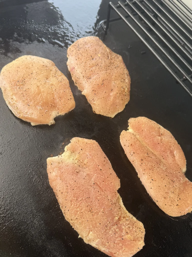 Raw boneless chicken breasts seasoned with garlic powder, smoked paprika, salt, and pepper.