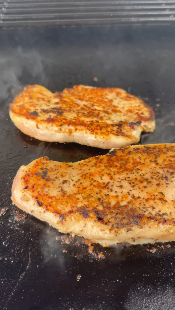 Grilled chicken breast topped on a griddle.