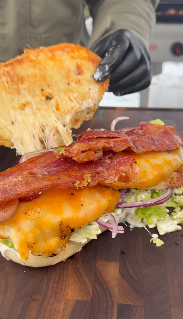 Brioche sandwich roll loaded with grilled chicken, crispy bacon, and fresh toppings, ready to serve.