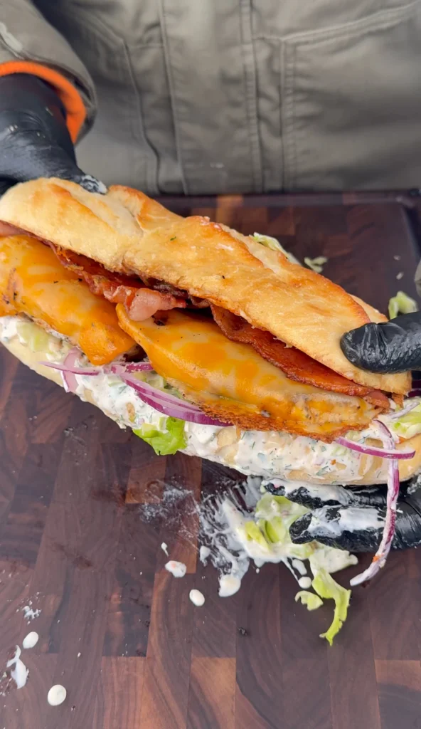 Chicken Bacon Ranch Sandwich served on a toasted brioche bun with lettuce, red onion, and melted cheese.