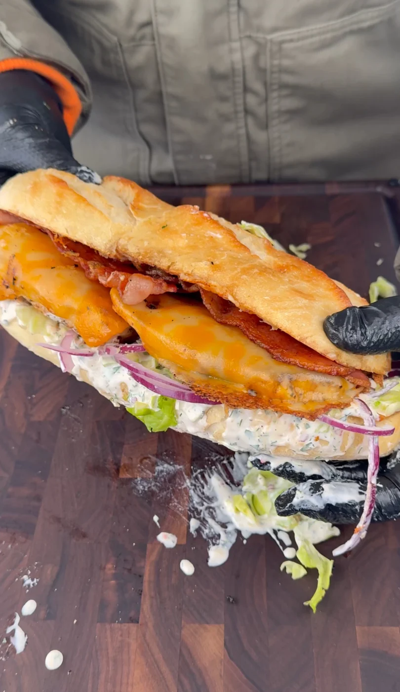 Chicken Bacon Ranch Sandwich served on a toasted brioche bun with lettuce, red onion, and melted cheese.