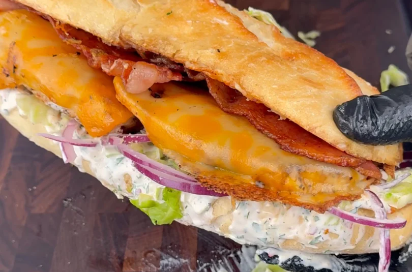 Chicken Bacon Ranch Sandwich served on a toasted brioche bun with lettuce, red onion, and melted cheese.
