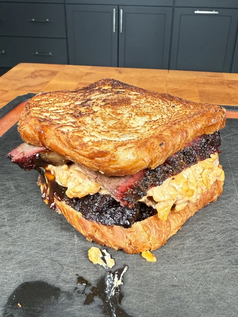 Close-up of a crispy brisket melt with melted pimento cheese oozing from the sides
