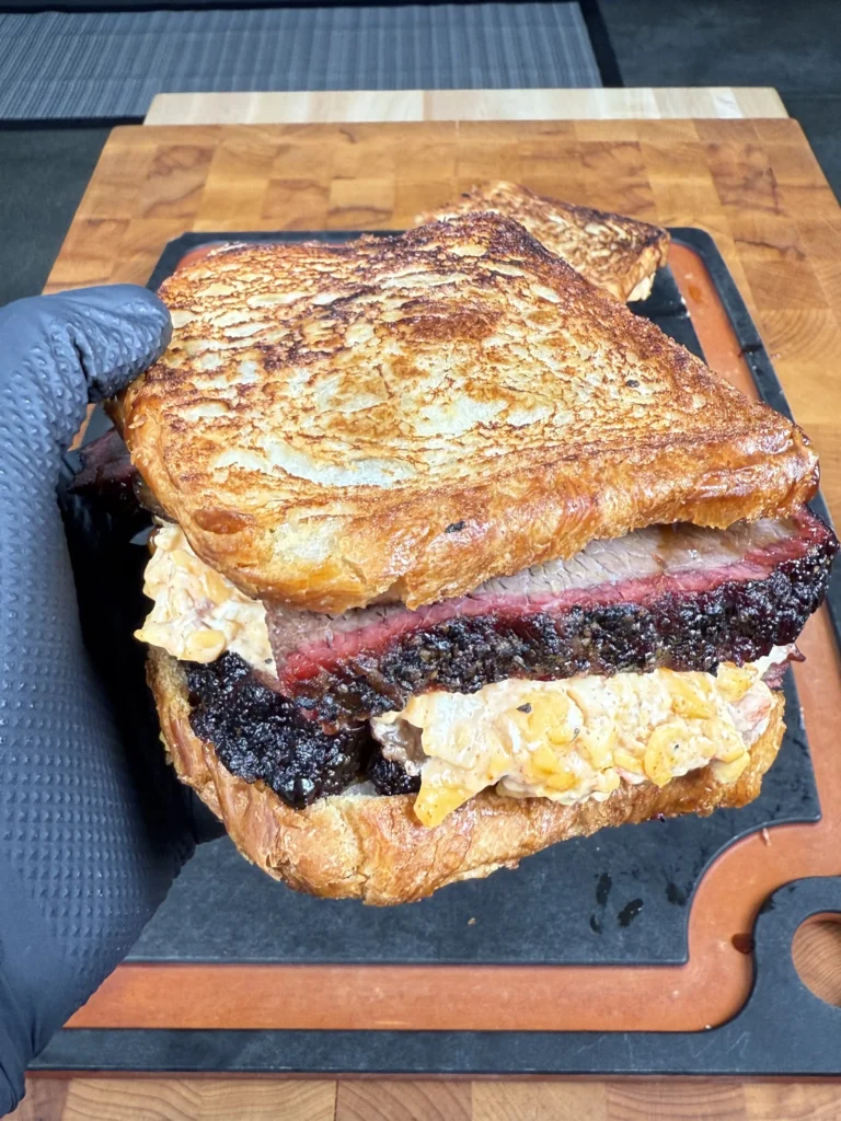 Golden, buttery sandwich being sliced in half to reveal melted cheese and brisket