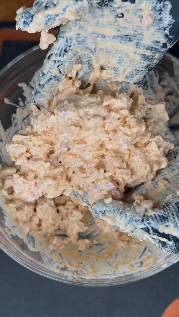Mixing shredded cheddar, cream cheese, and pimentos for homemade pimento cheese