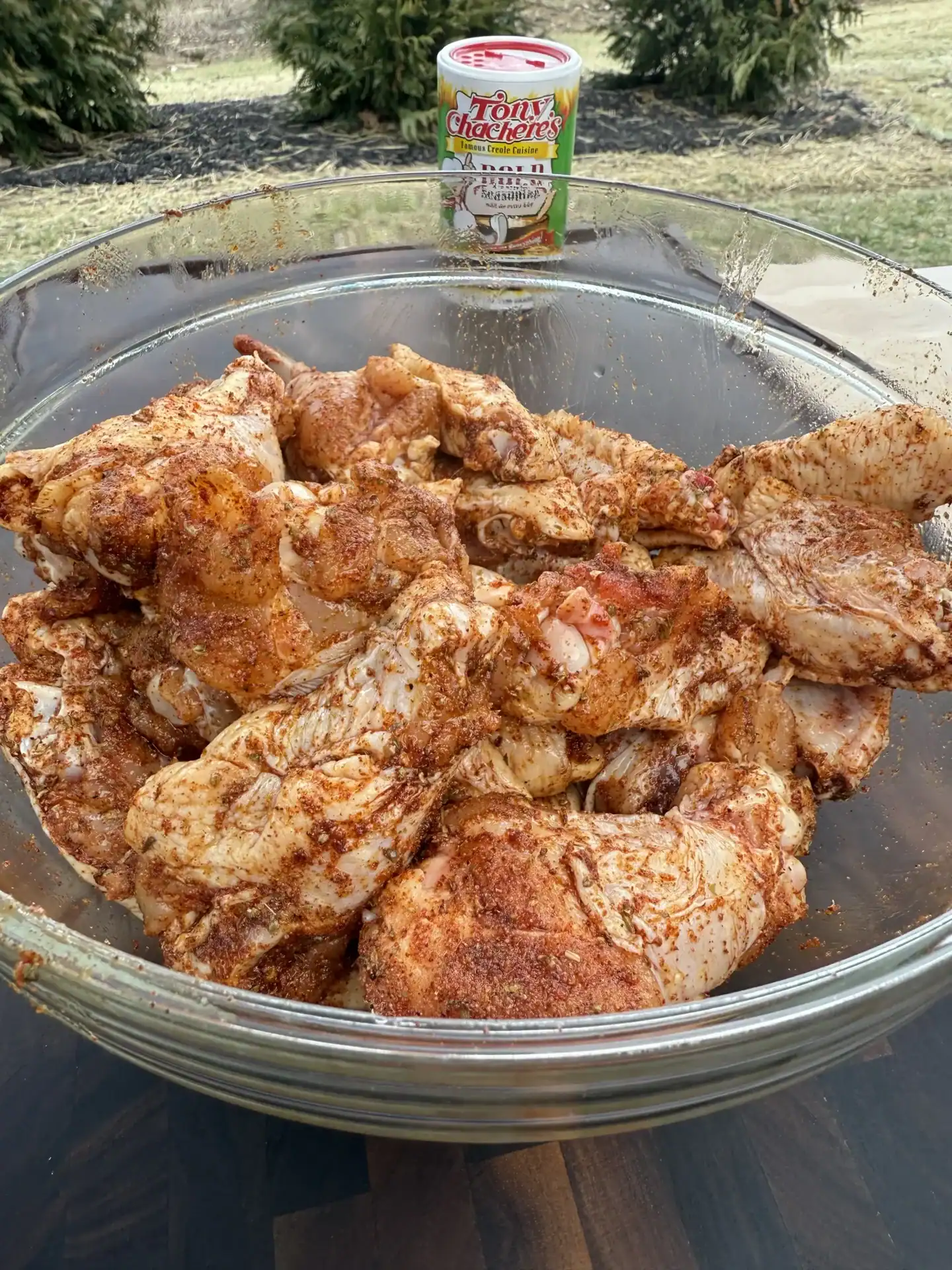raw, seasoned chicken wings placed in a glass bowl on a wooden countertop.