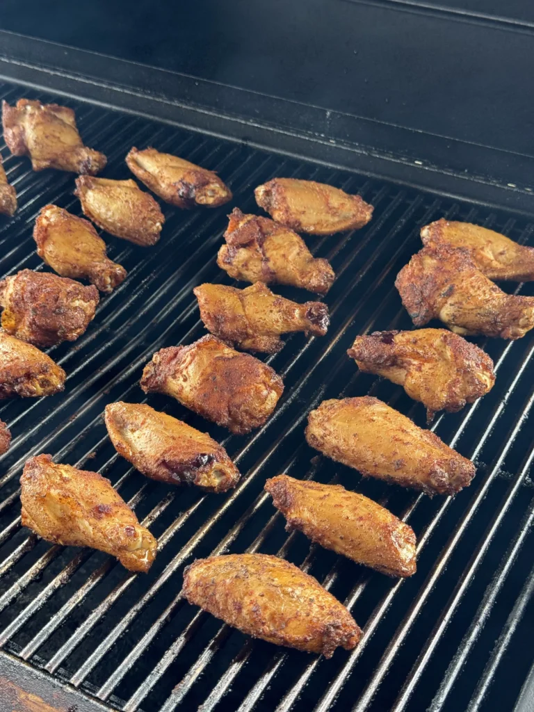 Chicken wings smoking on the grill with a light haze of smoke.