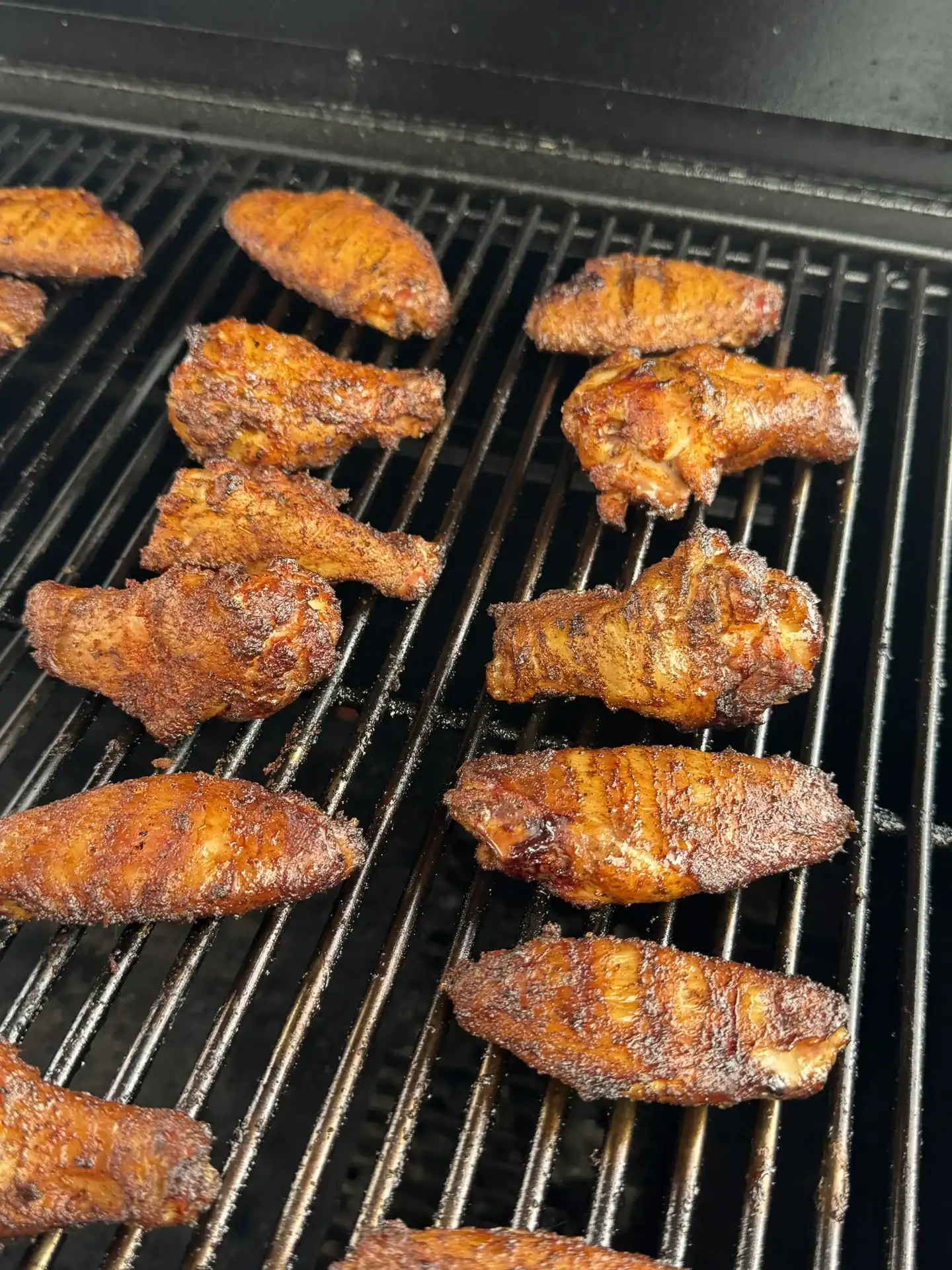 smoked chicken wings with grill marks placed on a wire rack on a smoker.