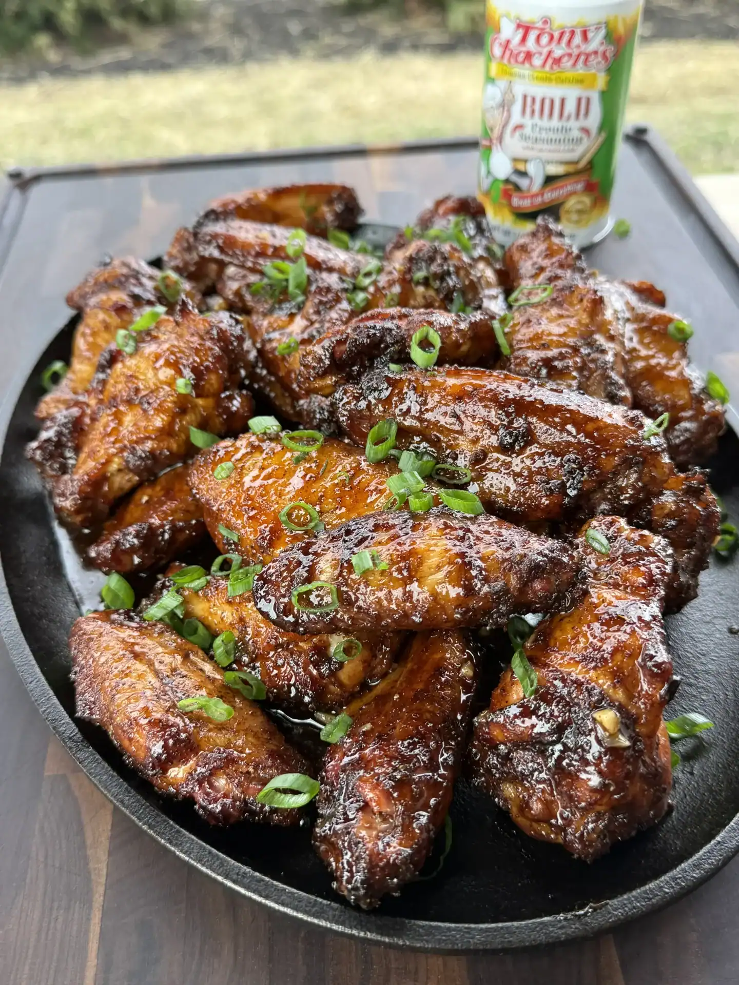 up close of the smoked hot honey chicken wings on a plate with Tony's seasoning in the background.