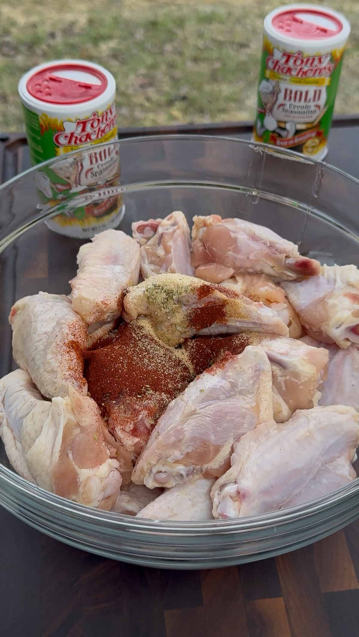 raw chicken wings seasoned with smoked paprika, garlic powder and other seasonings, in a glass bowl.