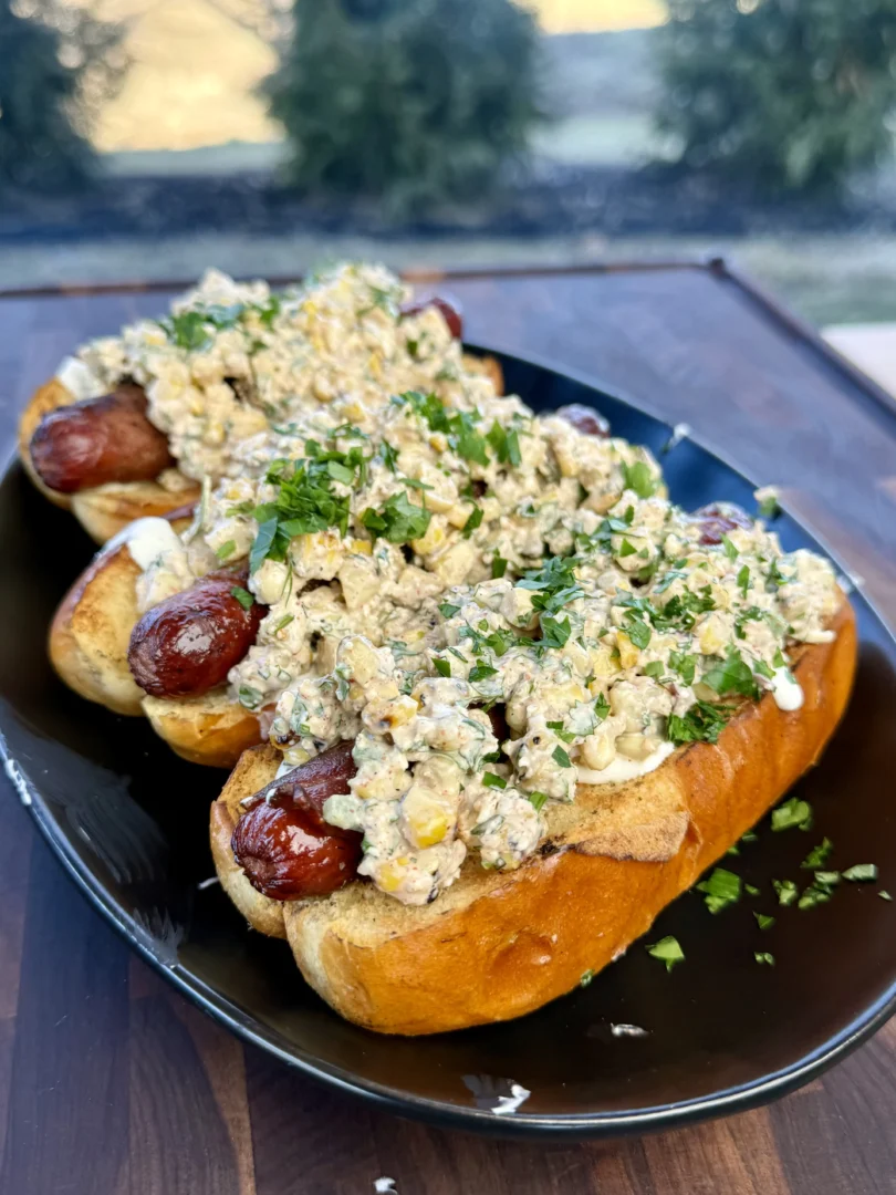 Elote hot dogs served outdoors on a sunny day.