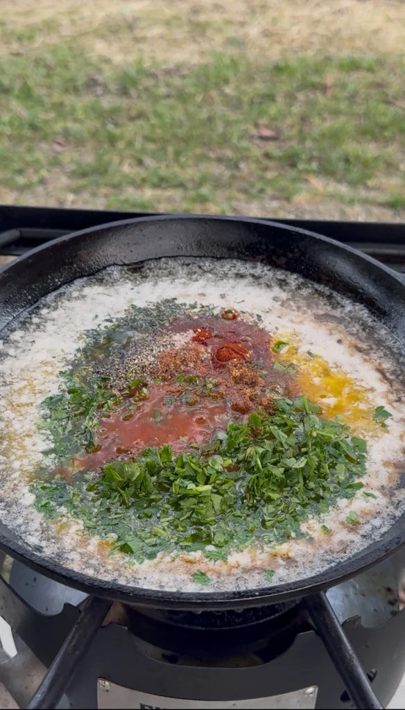 Steak being basted with melted butter in a skillet
