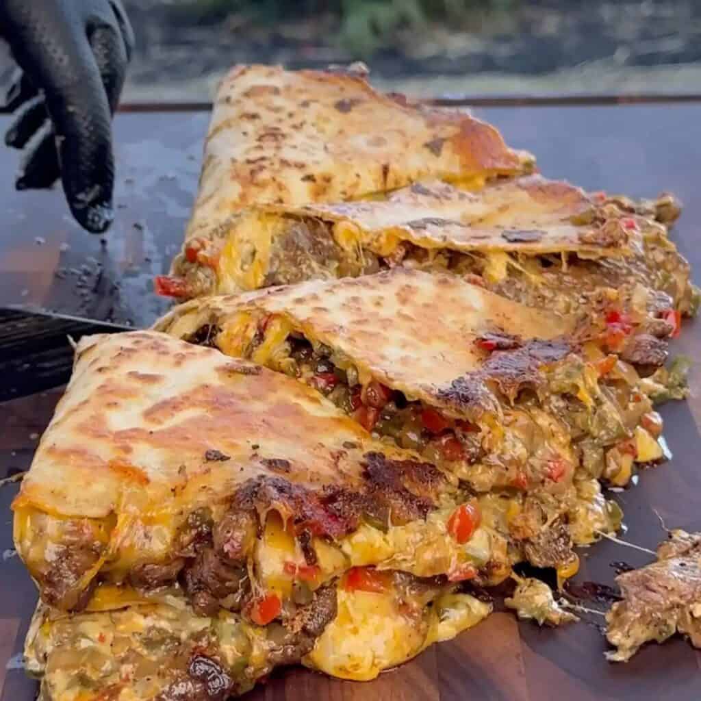 chili lime steak Fajita quesadillas on a flat-top grill, oozing with melted cheese and juicy steak.