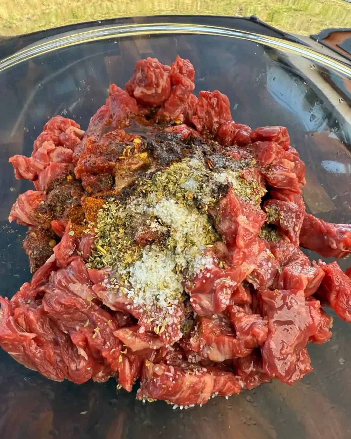 raw steak, seasonings and olive oil in a mixing bowl.
