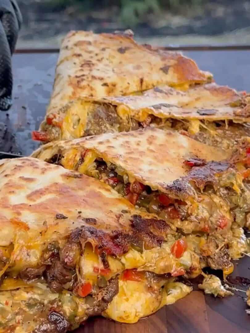 chili lime steak Fajita quesadillas on a flat-top grill, oozing with melted cheese and juicy steak.