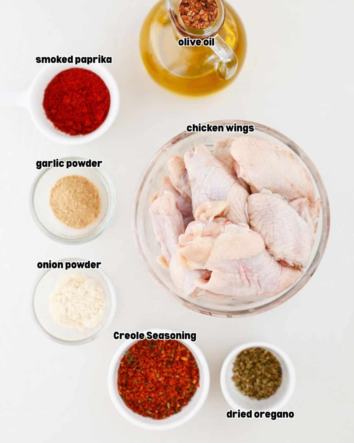 chicken wings and other ingredients for smoked hot honey chicken wings recipe placed in bowls on a kitchen countertop.
