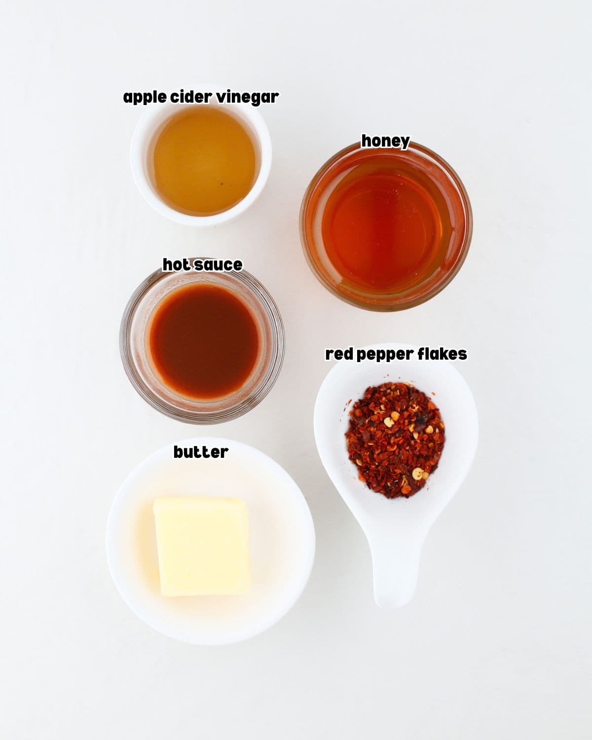 ingredients for the hot honey sauce placed in individual bowls on a kitchen countertop.
