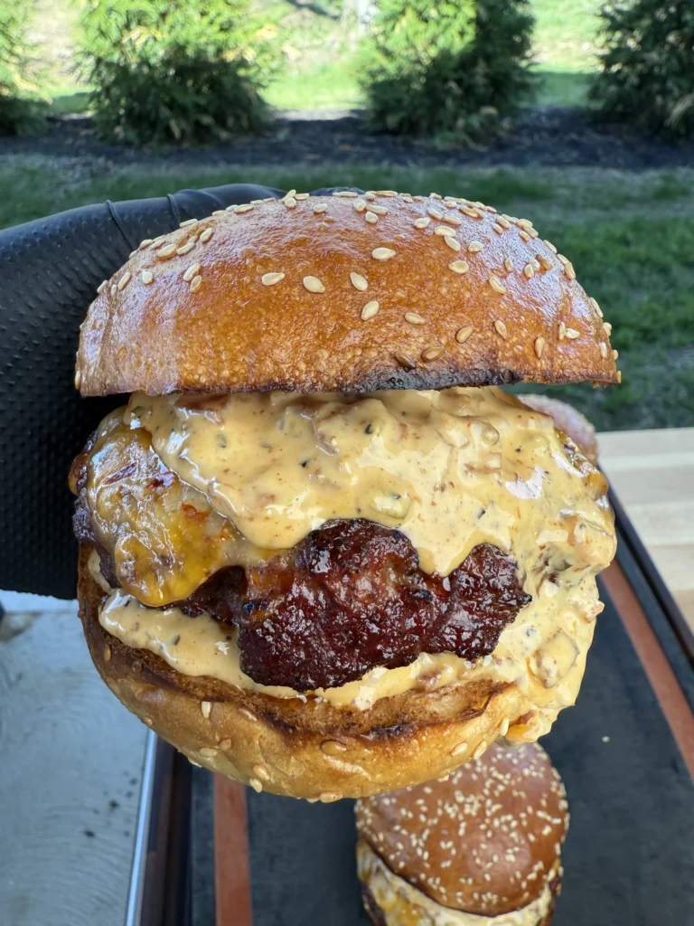 Close-up of melted cheese oozing from a smoked burger patty