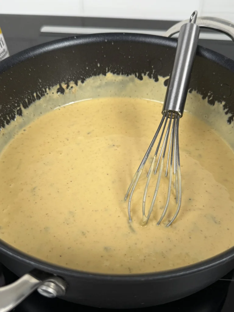 Cheese sauce with whisk in saucepan