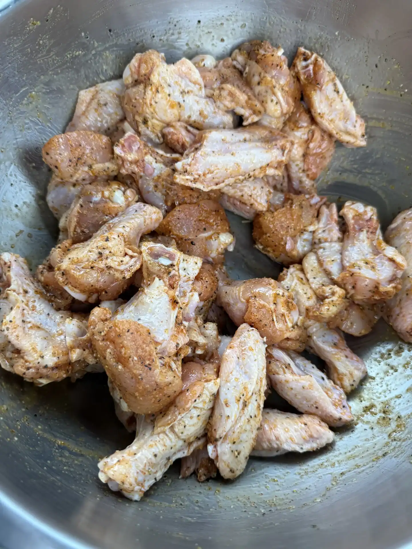 mixing bowl with seasoned raw chicken wings.