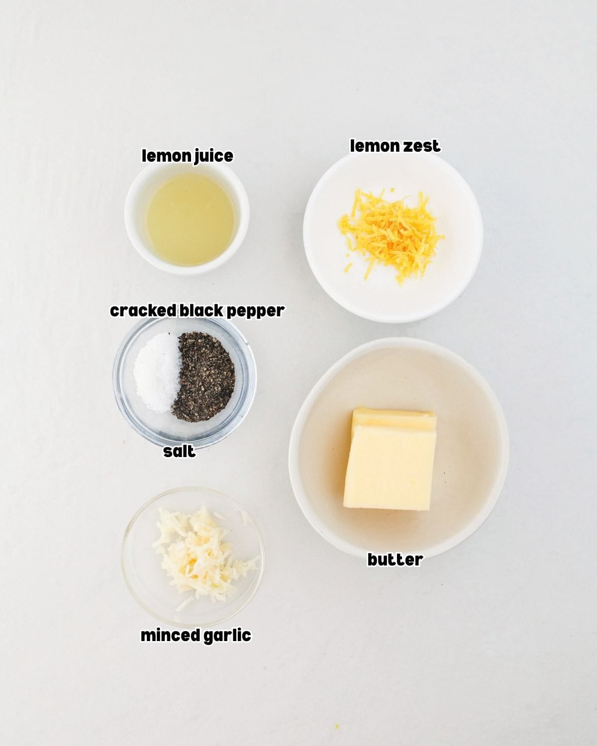 ingredients for garlic lemon pepper sauce arranged in small bowls on a kitchen countertop.
