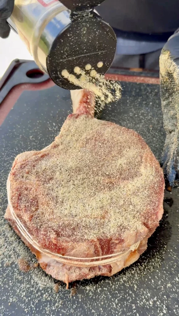 Salt pepper garlic seasoning coating on raw tomahawk steak surface