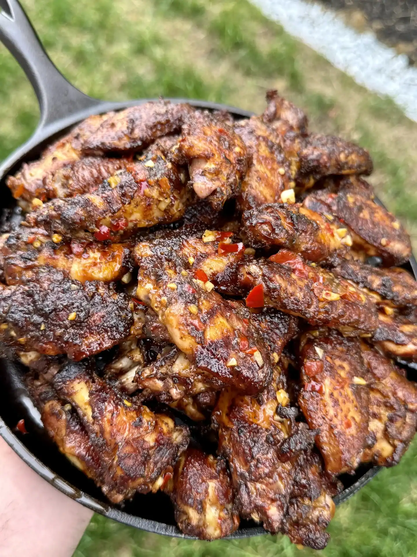 grilled chili lime chicken wings on a plate, with tiny specs of chopped red chilies.