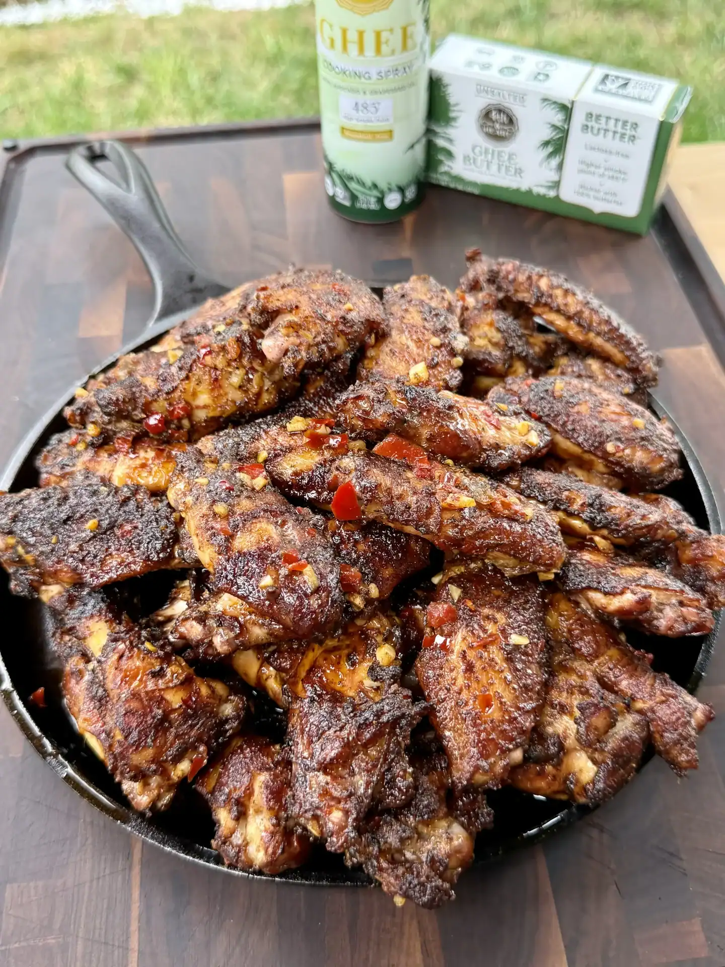 a saucepan stacked with saucy and spicy looking chicken wings placed on a wooden table.