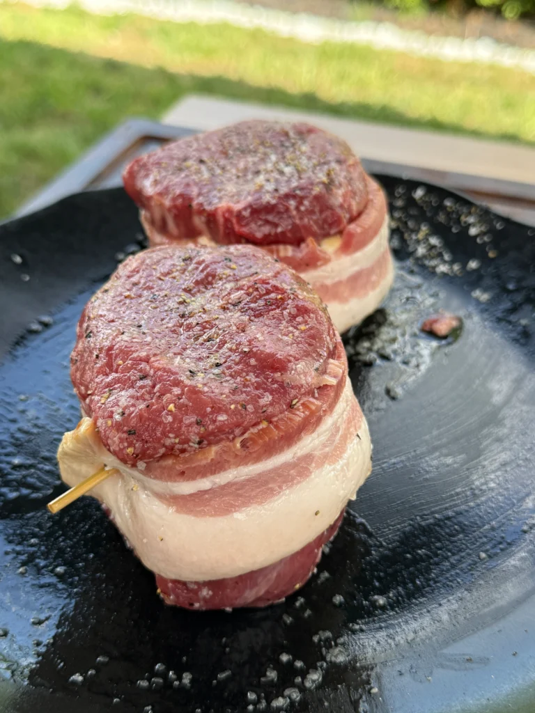 bacon wrapped filets on a plate with seasoning