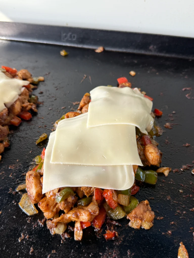 cheesesteaks on the griddle with cheese