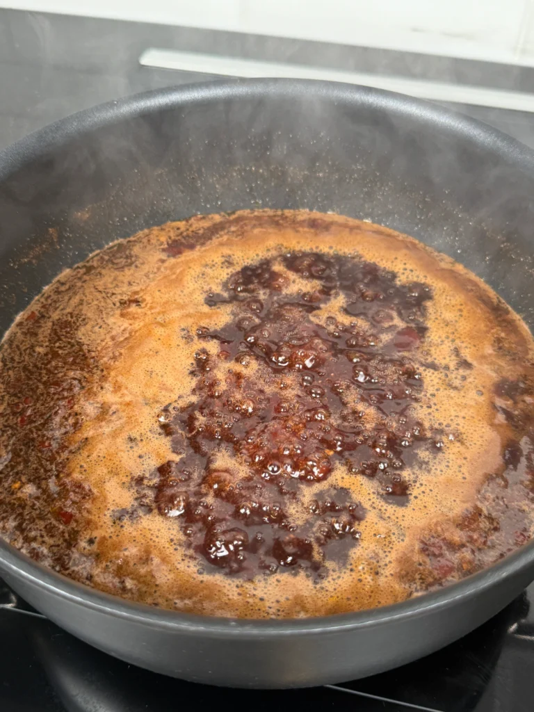 Cherry Dr Pepper chipotle glaze ingredients in a saucepan including chopped chipotle peppers and adobo sauce