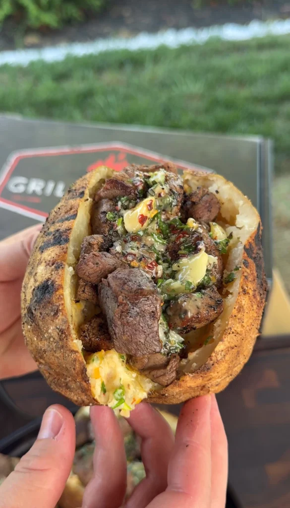 loaded baked potato with steak bites in a hand
