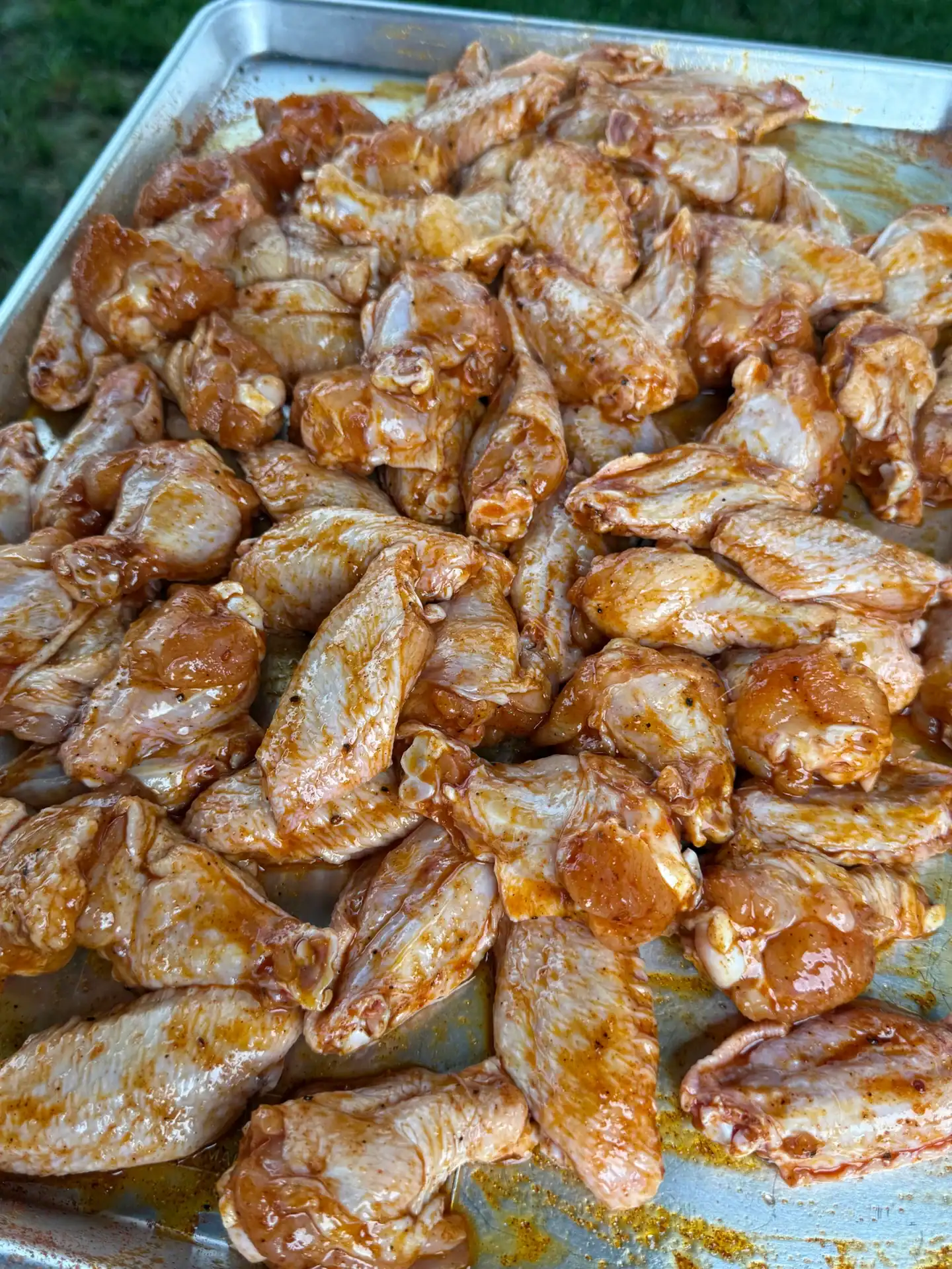 baking pan filled with raw chicken wings coated in oil and seasonings.