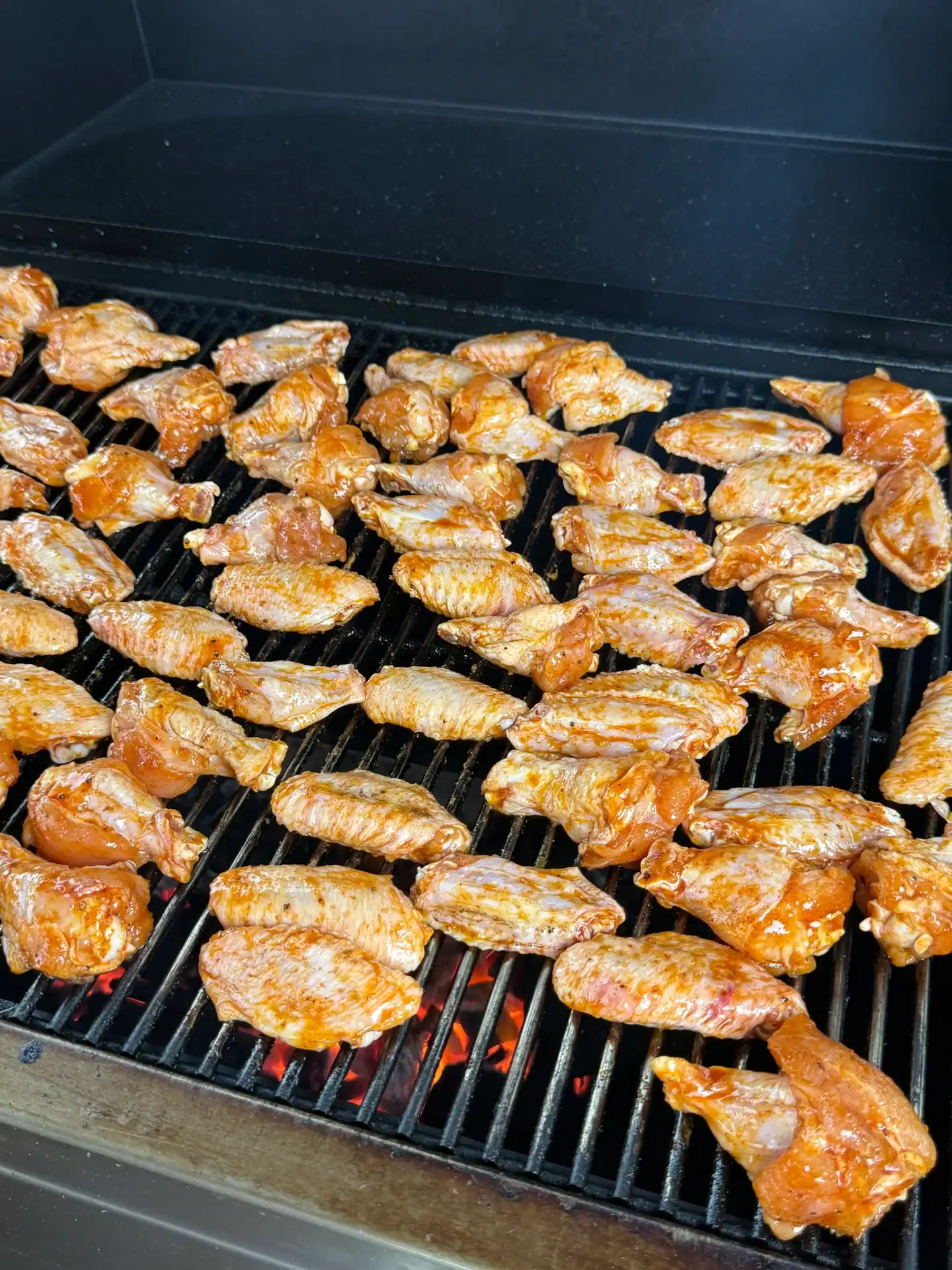 seasoned chicken wings arranged on a grill.
