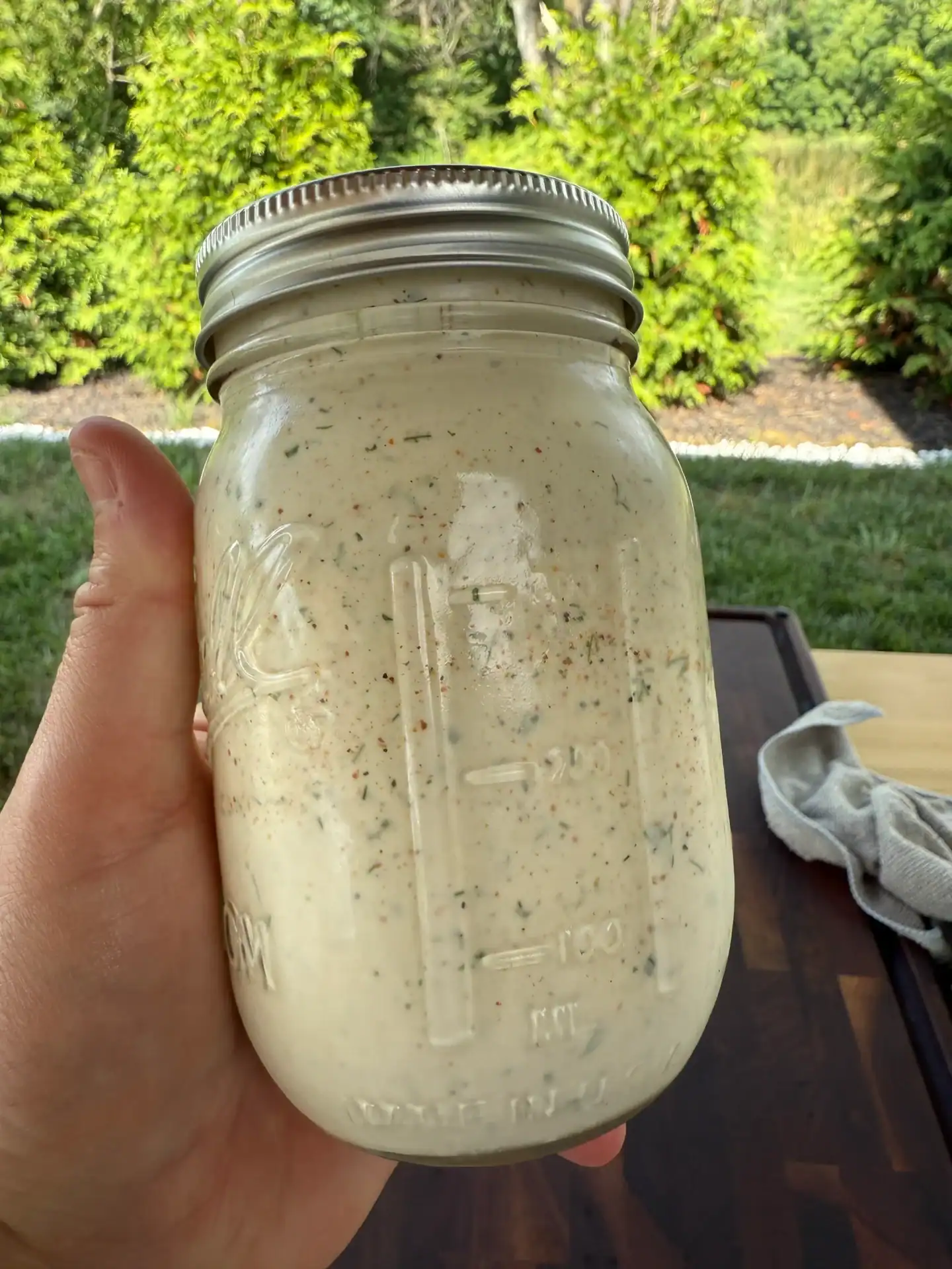 a hand holding a jar of Creole ranch sauce.