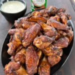 Smoked and grilled Creole chicken wings with Tony's ranch dip on a serving platter, showing crispy golden-brown skin and vibrant seasoning