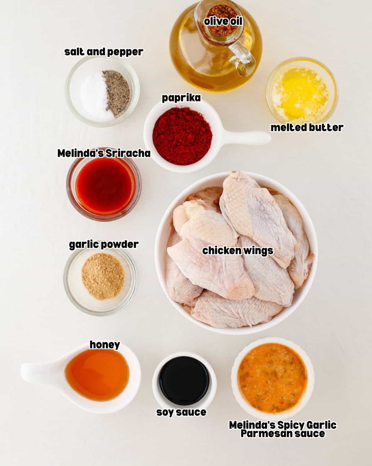 ingredients for spicy garlic parmesan chicken wings placed in bowls, on a kitchen countertop.
