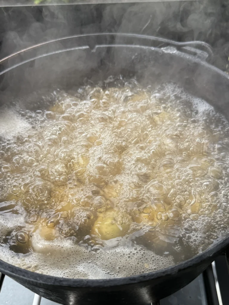 Chunked potatoes boiling rapidly in large pot with vigorous bubbling water, demonstrating proper cooking technique for tender results